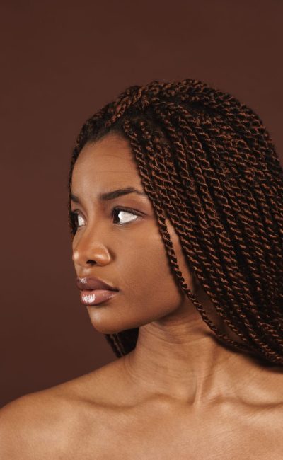 Half-naked black woman posing and looking aside isolated over brown background